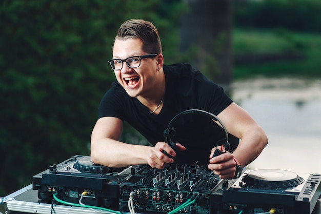 El joven DJ-hipster está ubicado detrás de la mesa de mezclas y tiene auriculares.