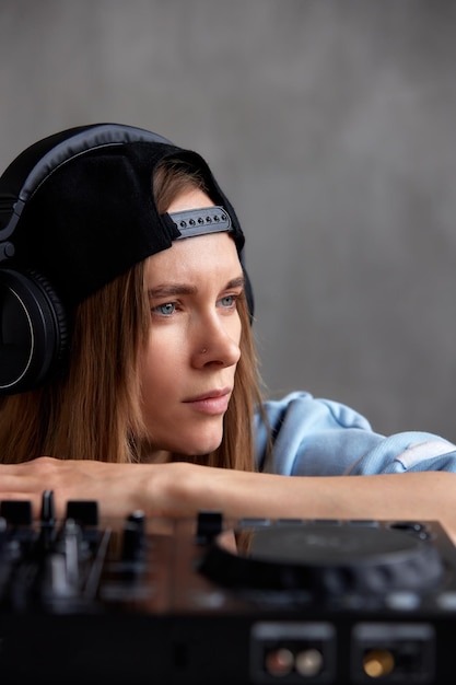 Una joven dj de pelo largo con un suéter azul y una gorra de béisbol negra posa con un dj negro