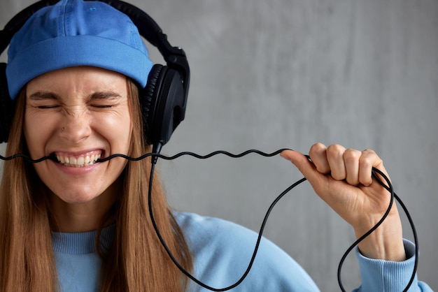 Una joven dj de pelo largo con un suéter azul y un sombrero divertido lleva auriculares en la cabeza y