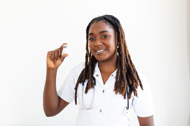 Una joven doctora africana tiene un fondo gris Sosteniendo una medicina revolucionaria en la mano