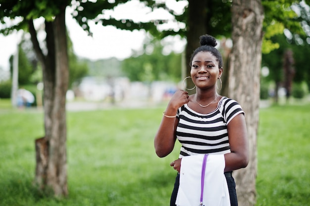 Joven doctora afroamericana mantenga bata blanca a mano con un estetoscopio presentado al aire libre.