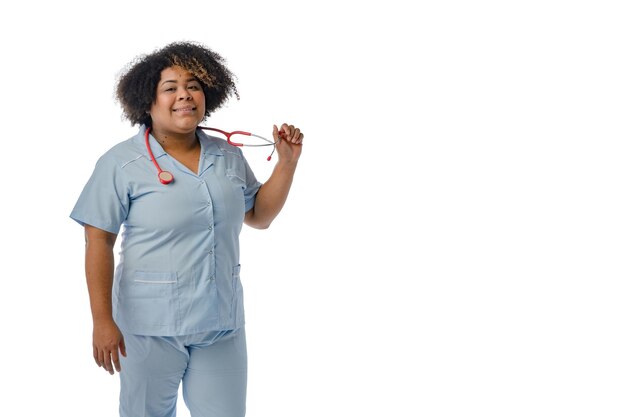 Joven doctora afrolatina sonriendo sosteniendo su estetoscopio de fondo blanco con espacio para copiar