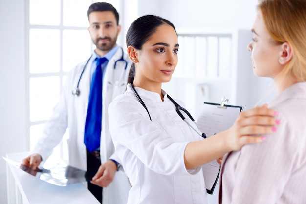 Foto joven doctora árabe explica el diagnóstico a un paciente en un hospital