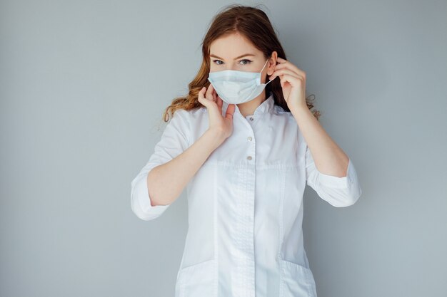 Joven doctora en una bata blanca y máscara médica. La medicina