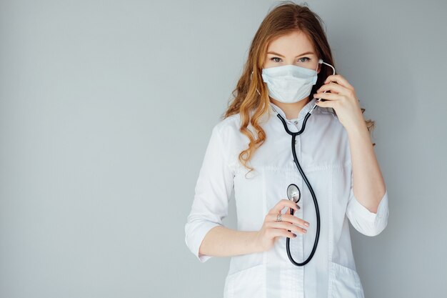 Joven doctora en una bata blanca y máscara médica. La medicina