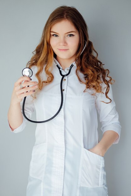 Joven doctora en una bata blanca y máscara médica. La medicina