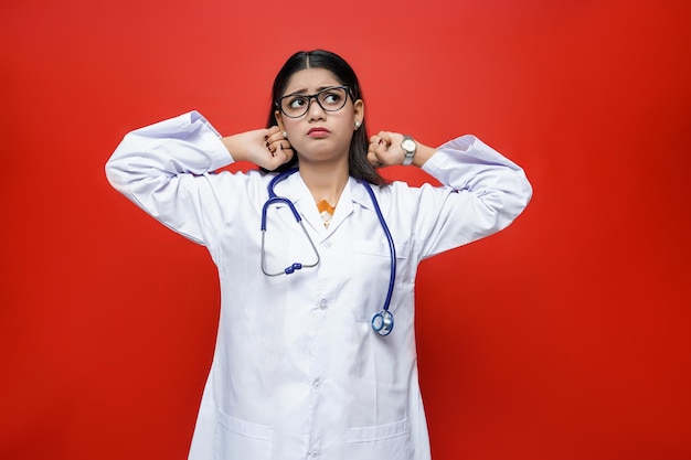 Joven doctora confundida vistiendo abrigo y estetoscopio alrededor del cuello modelo paquistaní indio