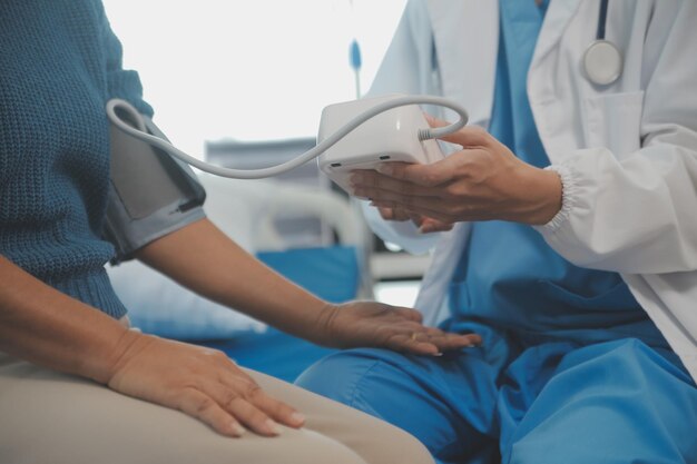 Joven doctora está usando un estetoscopio para escuchar los latidos del corazón del paciente Toma de una doctora dándole un chequeo a un paciente varón