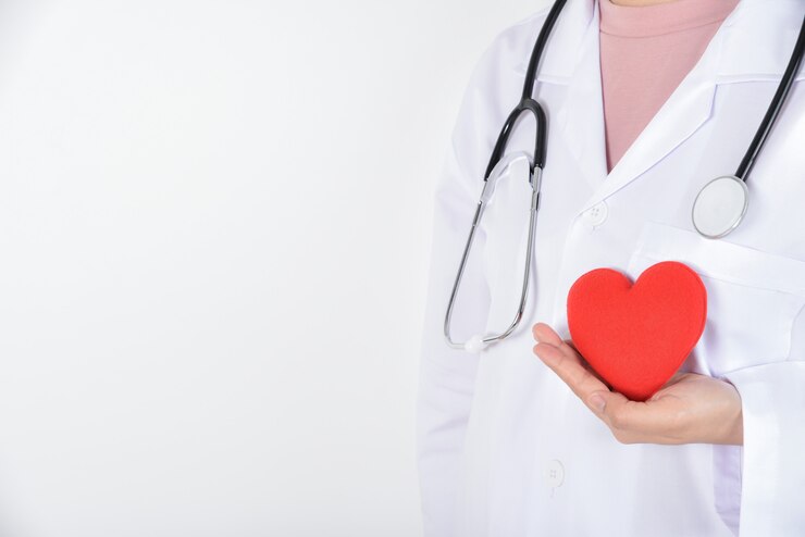 Joven doctora con estetoscopio con corazón rojo en su mano sobre blanco