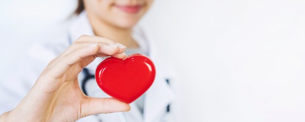 Joven doctora con el estetoscopio con corazón rojo