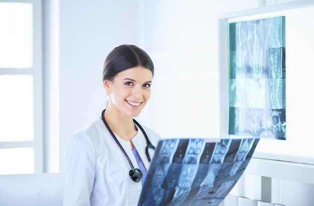 Joven doctora con estetoscopio examinando Xray en el consultorio del médico