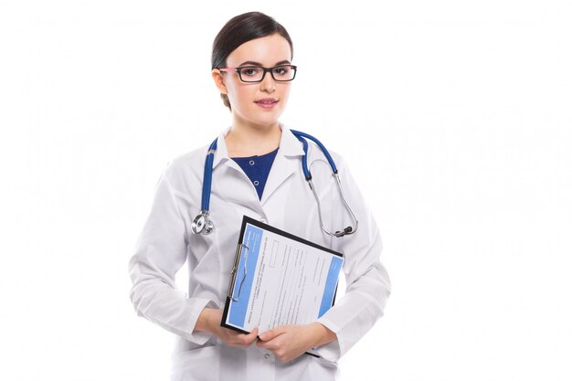 Joven doctora con estetoscopio con portapapeles en sus manos en uniforme blanco