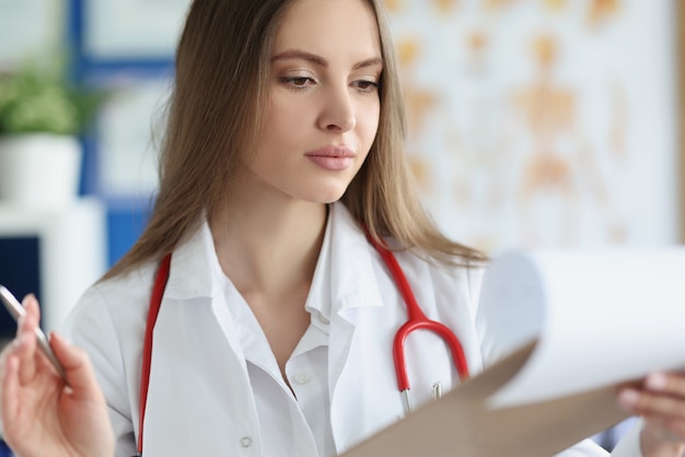 Joven doctora examina el historial médico del paciente