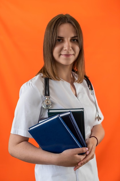 Una joven doctora con una gran sonrisa con dientes sostiene un retrato de libro de una enfermera aislada con uniforme blanco