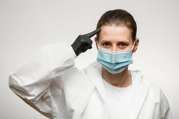 Joven doctora en máscara médica que señala con el dedo a la cabeza.