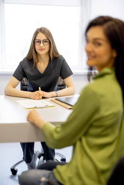 Foto una joven doctora con una mujer en la oficina.