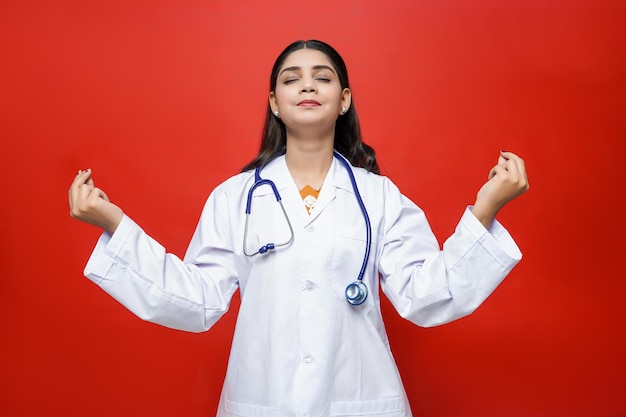 Joven doctora ojos cerrados sensación relajarse vistiendo abrigo y estetoscopio modelo paquistaní indio