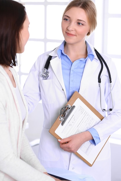 Joven doctora y paciente en un examen médico en el consultorio del hospital. Se ve bien la blusa color azul de terapeuta. Concepto de medicina y salud.