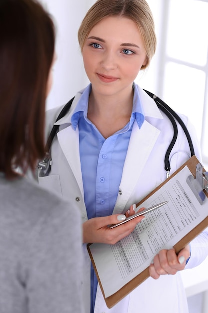 Joven doctora y paciente en un examen médico en el consultorio del hospital. Se ve bien la blusa color azul de terapeuta. Concepto de medicina y salud.