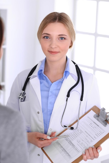 Joven doctora y paciente en un examen médico en el consultorio del hospital. Se ve bien la blusa color azul de terapeuta. Concepto de medicina y salud.