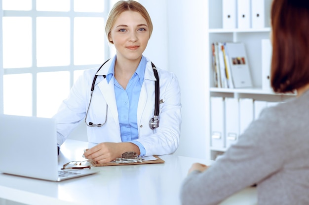 Joven doctora y paciente en un examen médico en el consultorio del hospital. Se ve bien la blusa color azul de terapeuta. Concepto de medicina y salud.