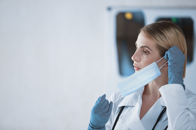 Una joven doctora se pone una mascarilla protectora antes del trabajo