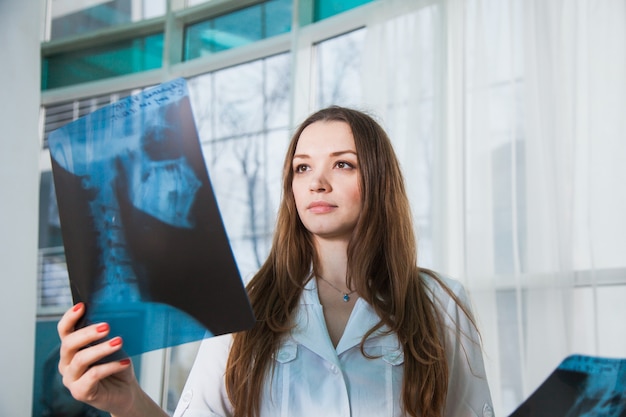 Joven doctora profesional examinando la radiografía del cráneo humano del paciente durante una visita. Concepto de medicina de salud