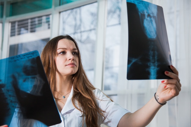 Joven doctora profesional examinando la radiografía del cráneo humano del paciente durante una visita. Concepto de medicina de salud