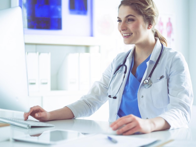 Joven doctora sentada en un escritorio y trabajando en la computadora en la oficina del hospital Seguro de salud y concepto de ayuda Médico listo para examinar al paciente