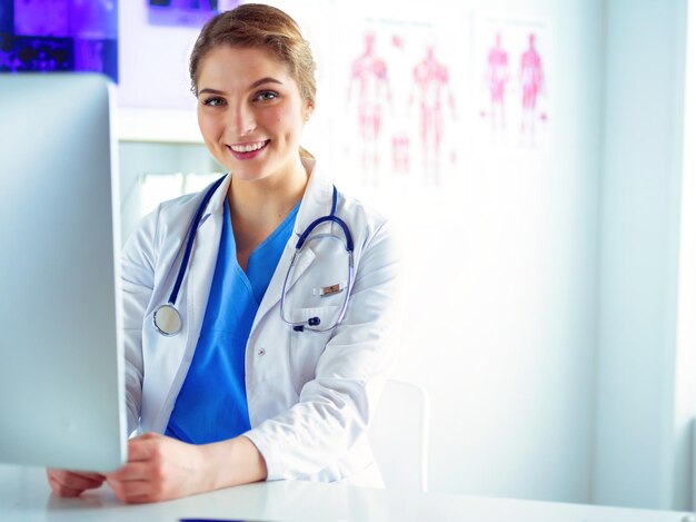 Joven doctora sentada en un escritorio y trabajando en la computadora en la oficina del hospital Seguro de salud y concepto de ayuda Médico listo para examinar al paciente