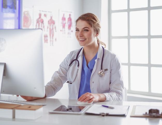 Joven doctora sentada en un escritorio y trabajando en la computadora en la oficina del hospital Seguro de salud y concepto de ayuda Médico listo para examinar al paciente