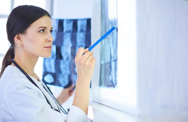 Joven doctora sonriente con estetoscopio apuntando a Xray en el consultorio del médico