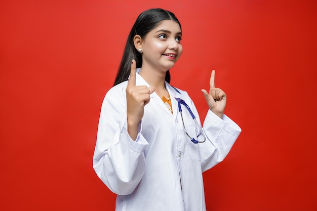 Joven doctora con sonrisa vistiendo abrigo y estetoscopio alrededor del cuello m paquistaní indio