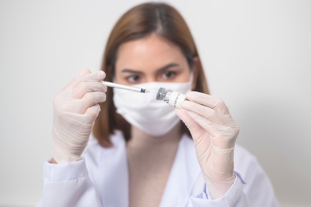 Foto una joven doctora sosteniendo una jeringa con una botella de vacuna covid-19 para inyección, vacunación covid-19 y concepto de atención médica