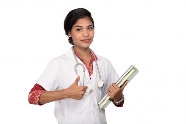 Joven doctora sosteniendo libro con estetoscopio