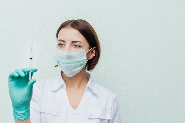 Joven doctora sostiene una jeringa en la mano y la mira. Concepto de antibióticos