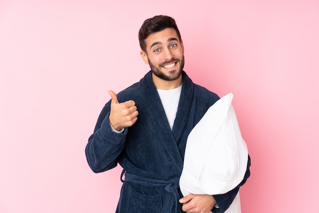 Joven va a dormir en la pared rosa dando un gesto de pulgares arriba