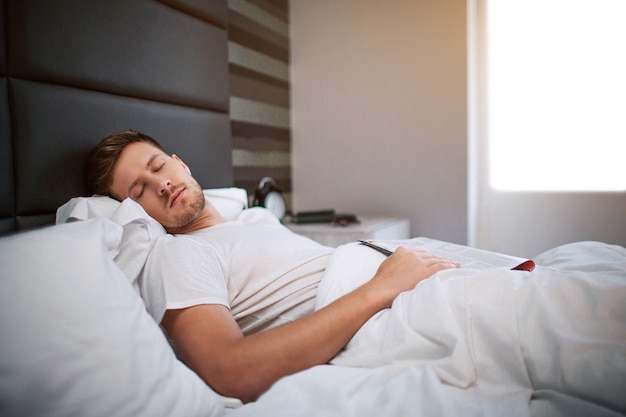 Joven durmiendo en la cama por la mañana