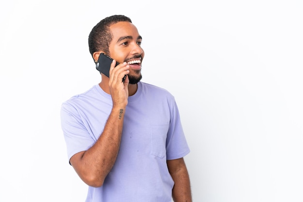 Joven ecuatoriano aislado de fondo blanco manteniendo una conversación con el teléfono móvil