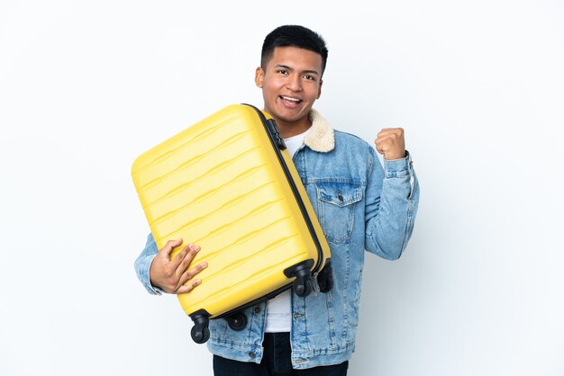 Joven ecuatoriano aislado en la pared blanca en vacaciones con maleta de viaje