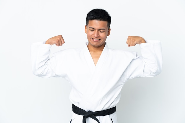 Joven ecuatoriano haciendo karate aislado sobre fondo blanco haciendo gesto fuerte