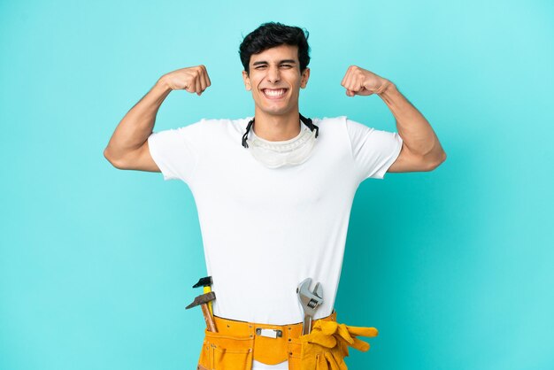 Joven electricista argentino aislado sobre fondo azul haciendo un gesto fuerte