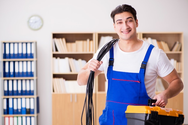 Joven electricista con cable trabajando en oficina