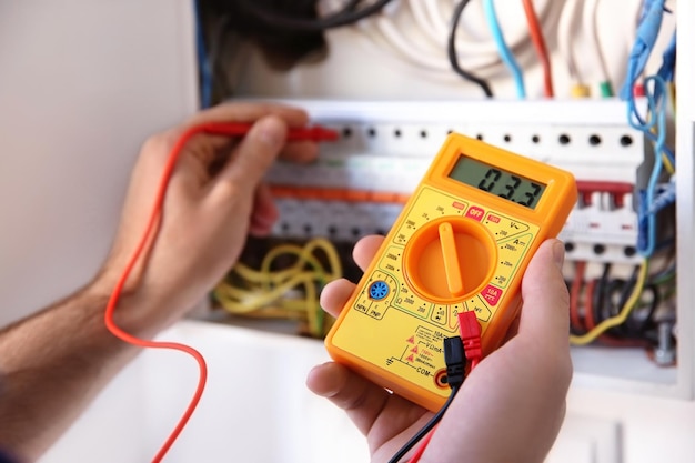 Joven electricista midiendo voltaje en tablero de distribución