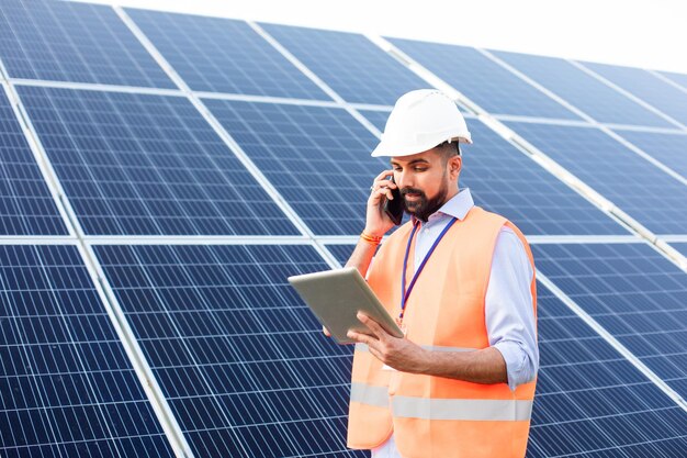 El joven electricista trabaja en una estación solar usando aparatos