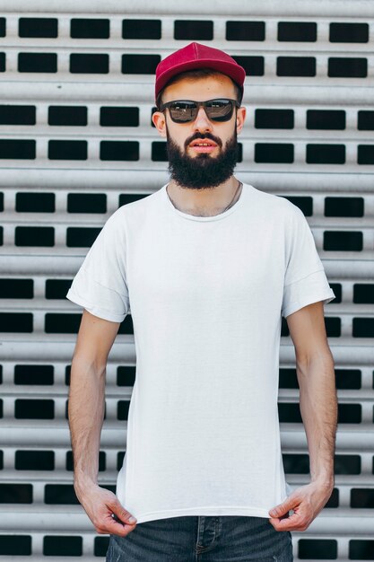 Un joven elegante con barba en una camiseta blanca y gafas