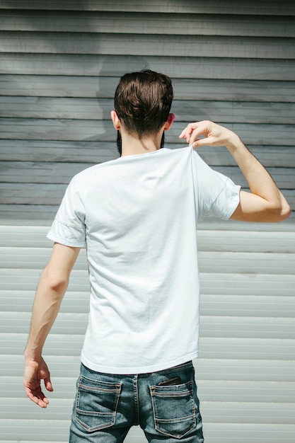 Un joven elegante con barba en una camiseta blanca y gafas