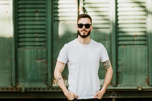 Joven elegante con barba en una camiseta blanca y gafas