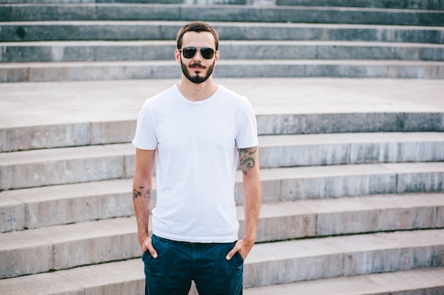 Un joven elegante con barba en una camiseta blanca y gafas