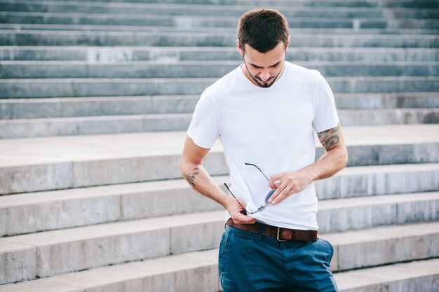 Un joven elegante con barba en una camiseta blanca y gafas